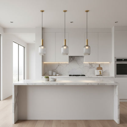Trois suspensions goodlampe en verre fumé gris et métal doré au-dessus d'un îlot de cuisine en marbre blanc moderne